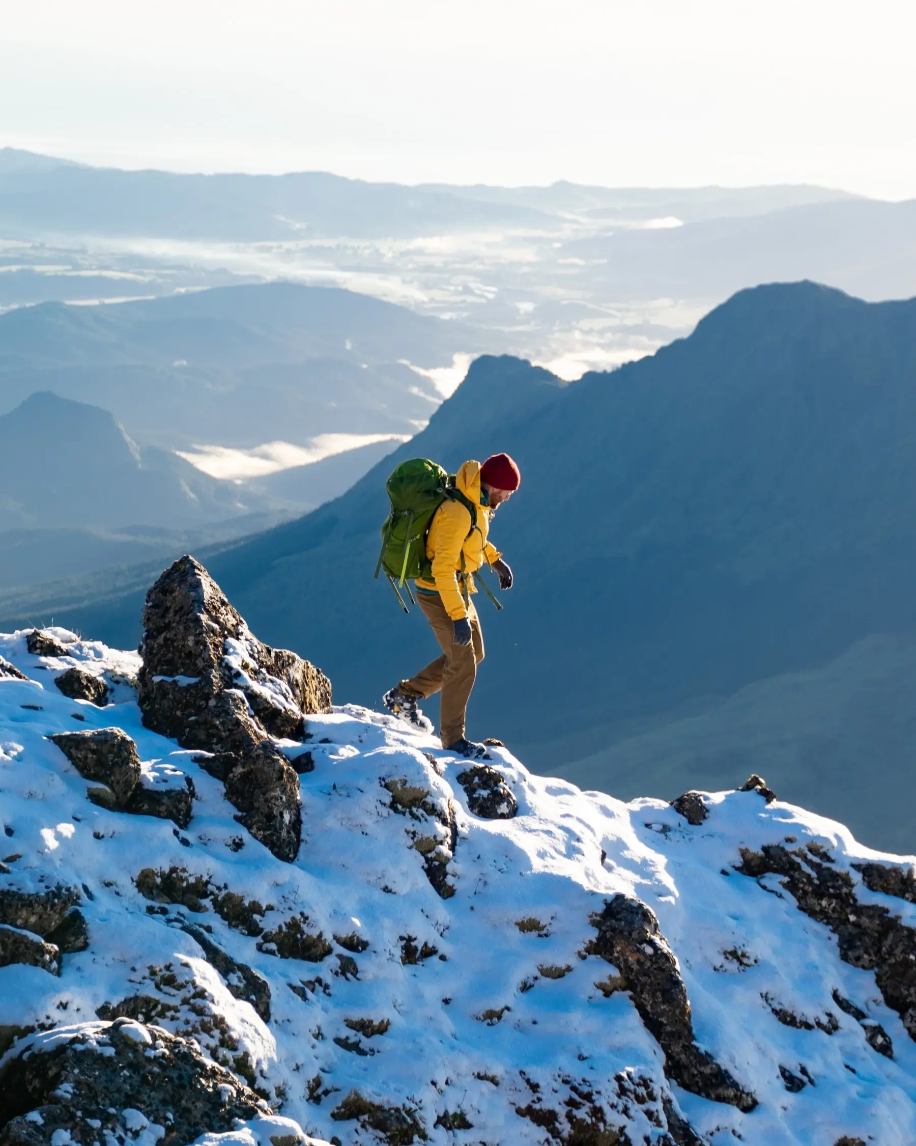 Hiker on snow-capped Mount Hikurangi, Gisborne, with sweeping views in background. Image credit: Tourism NZ/Eric Hanson