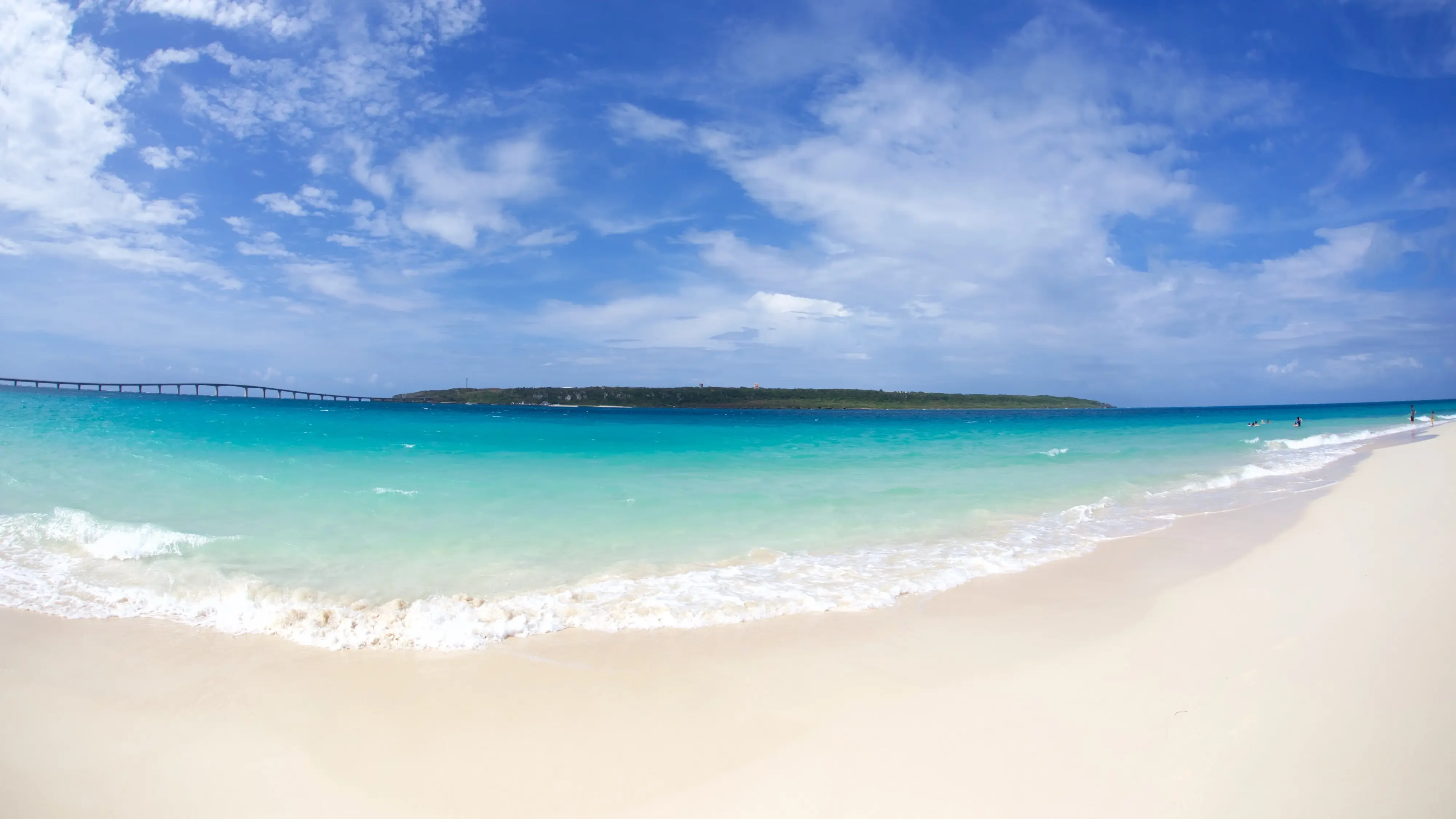 Stretch of white sand and turquoise water at Maehama Beach, Miyako Island, with Kurima bridge and island in background. Image credit: stock.adobe.com