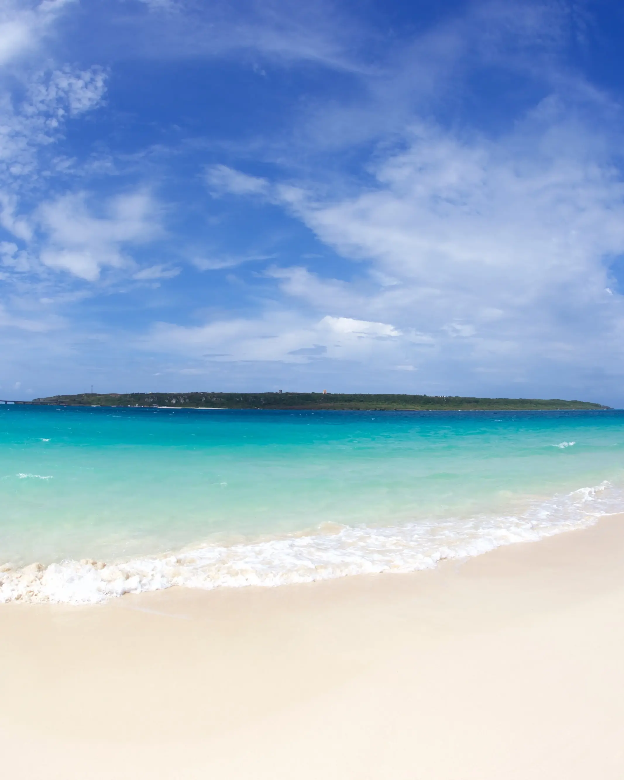 Stretch of white sand and turquoise water at Maehama Beach, Miyako Island, with Kurima bridge and island in background. Image credit: stock.adobe.com