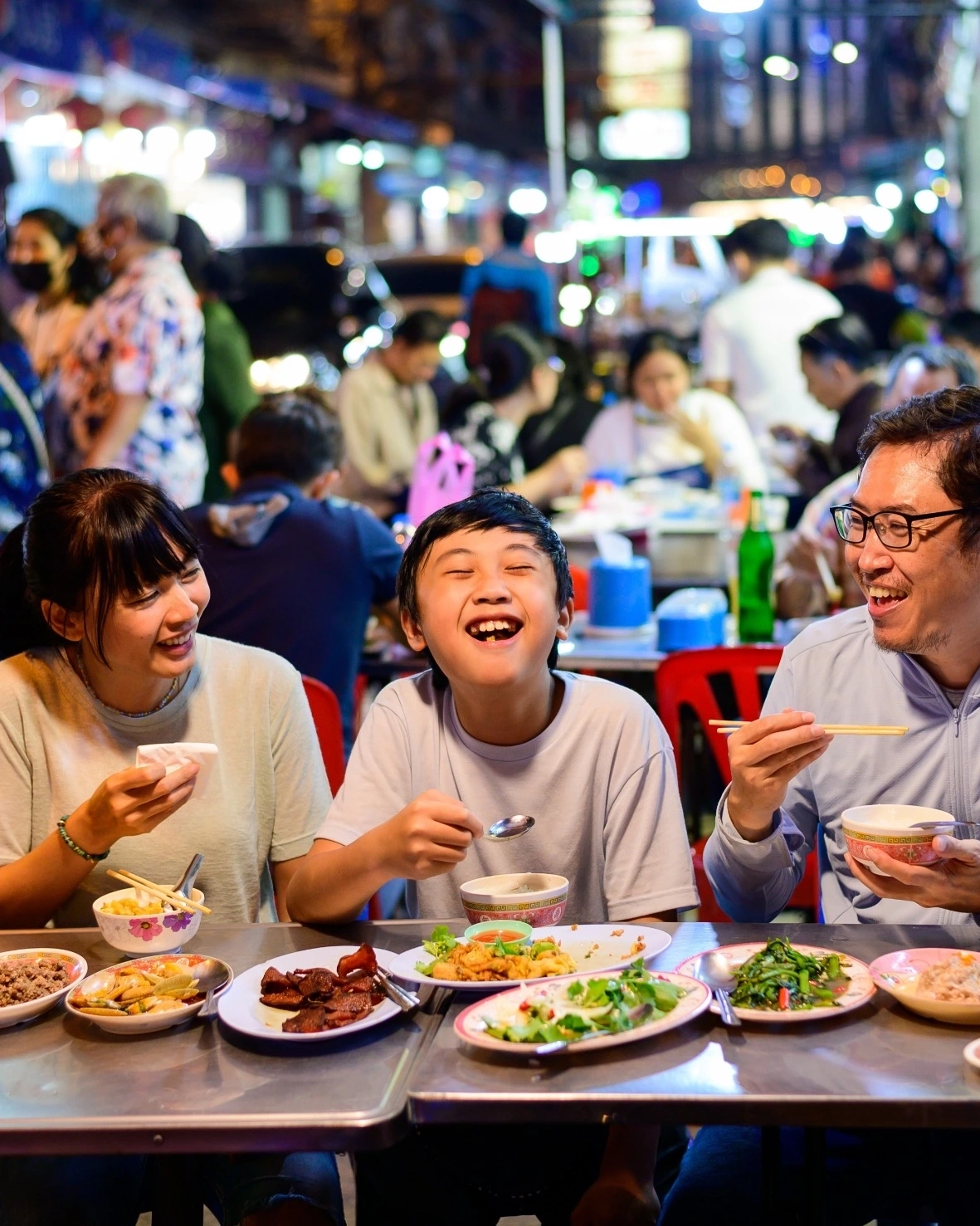 Asian family enjoying a meal at a night market in Bangkok, Thailand.