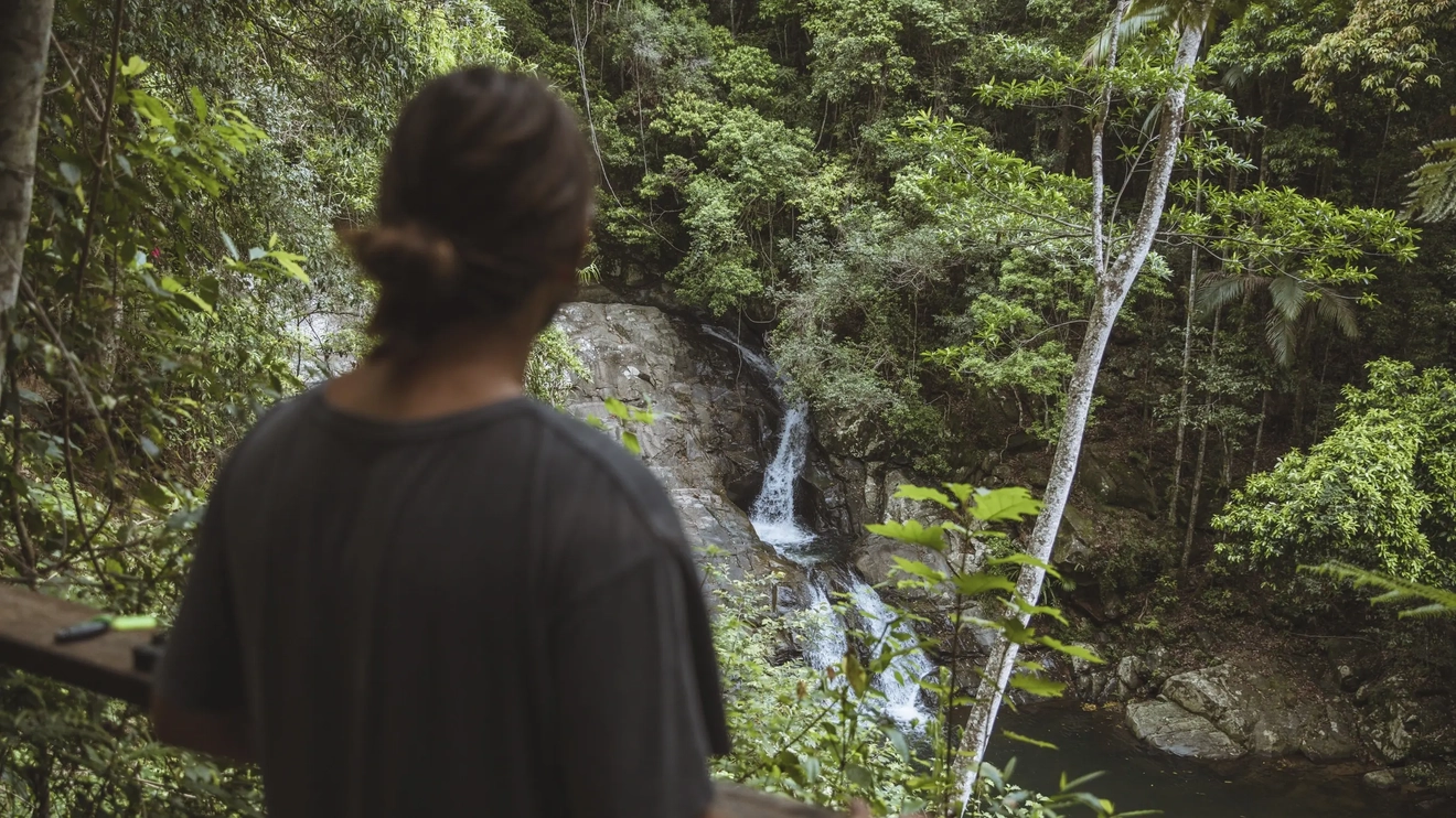 Person looking out over waterfall tumbling into Currumbin Rock Pools, Gold Coast. Image credit: Tourism and Events Queensland