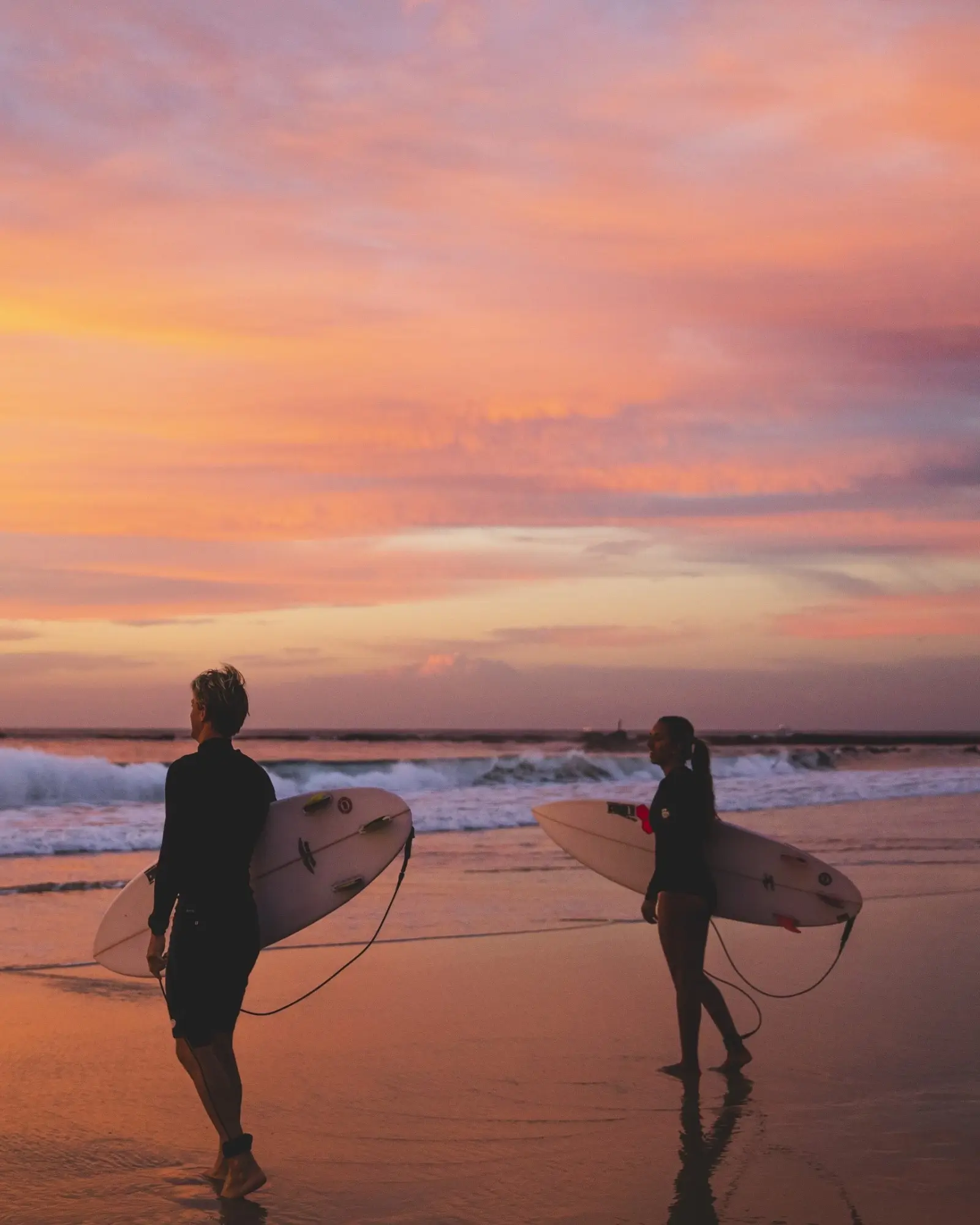 Two surfers on the beach at dawn, holding surfboards, looking at the waves, at Nobbys Beach, Newcastle. Image credit: Destination NSW