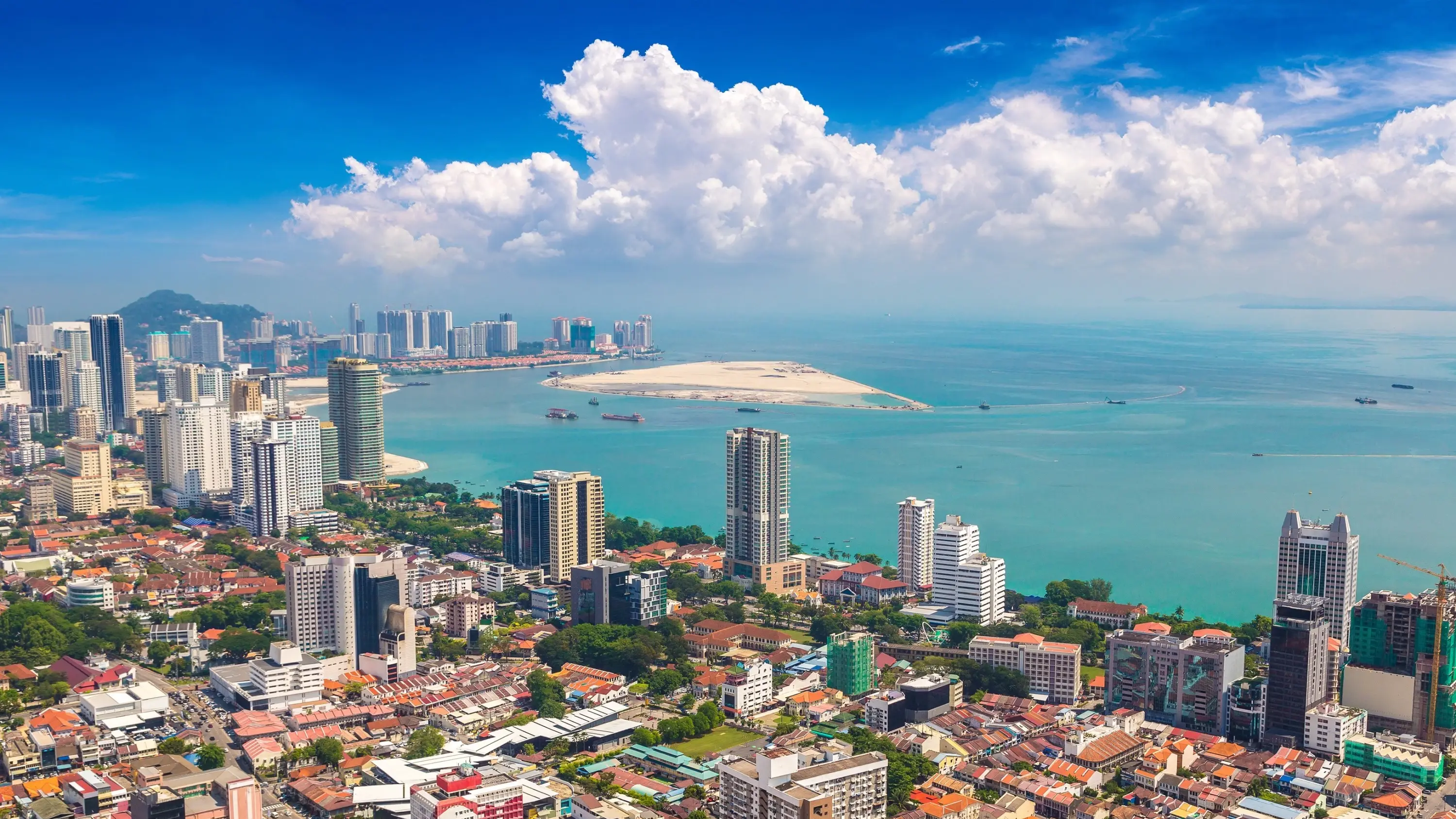 Aerial view of Georgetown, Penang, on a sunny day, with skyscrapers on the city skyline fronting onto the sea. Image credit: stock.adobe.com