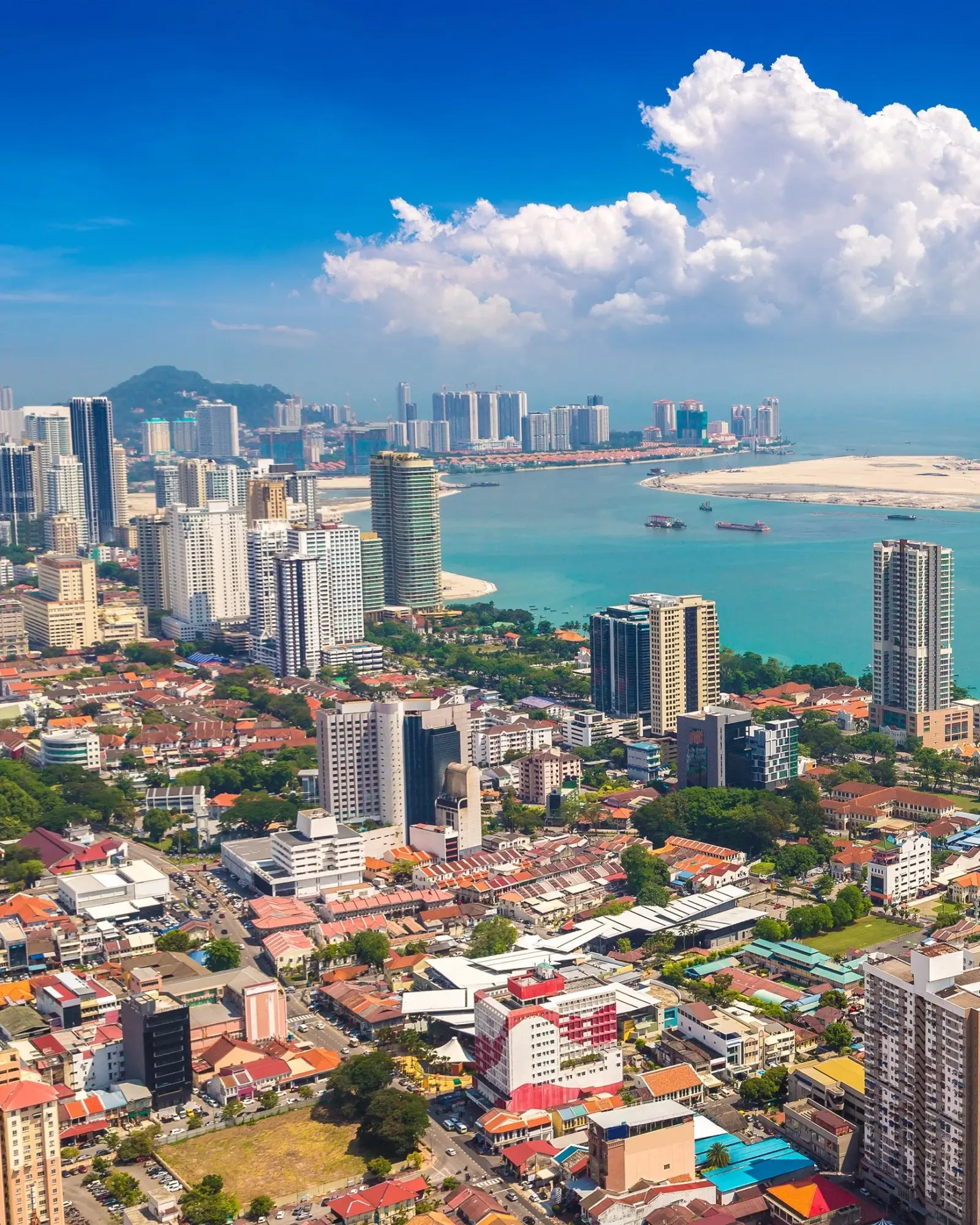 Aerial view of Georgetown, Penang, on a sunny day, with skyscrapers on the city skyline fronting onto the sea. Image credit: stock.adobe.com