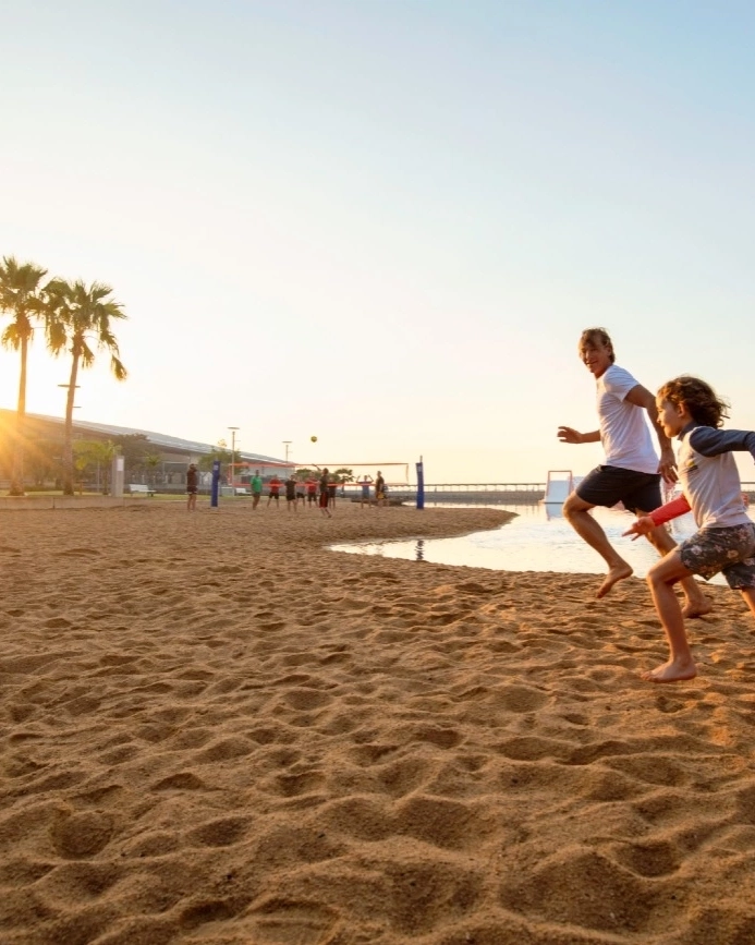 Kids and adult run on the sand at Darwin Waterfront. Image credit: Tourism NT/Shaana McNaught