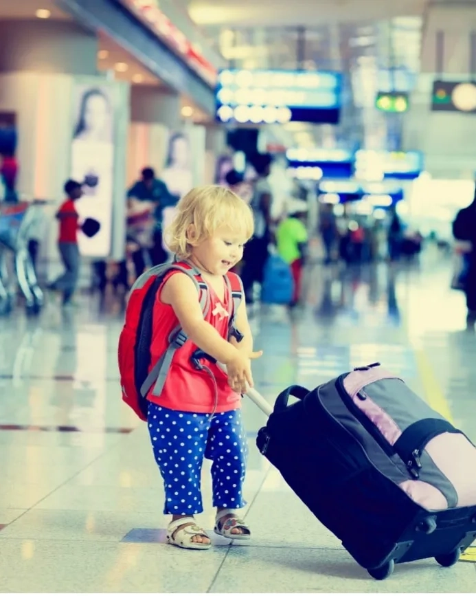 A little girl with a suitcase in an airport.