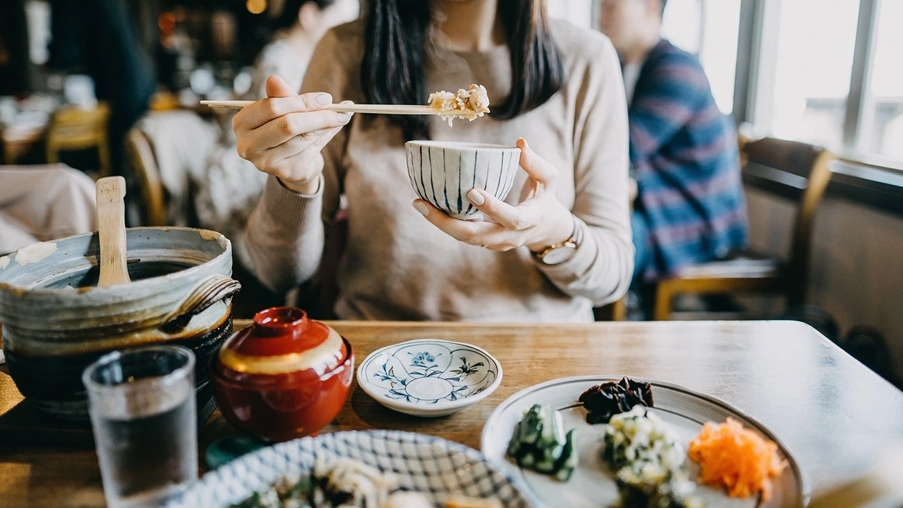 A woman eats with chopsticks at a restaurant in Tokyo, Japan.