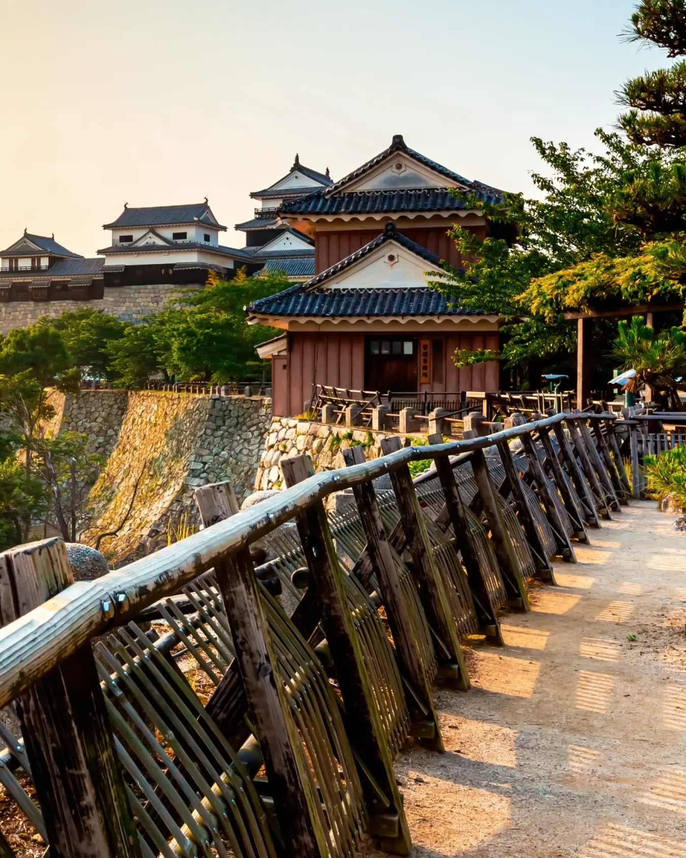 View of Matsuyama castle, fenced path and green forest, Matsuyama, Japan. Image credit: stock.adobe.com