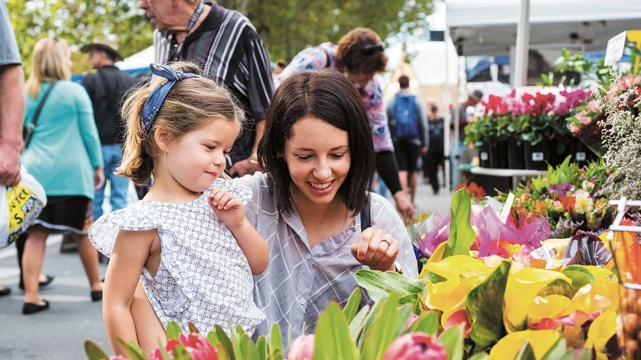 A mother and daughter look at a flower stall at Hobart's Salamanca Market.