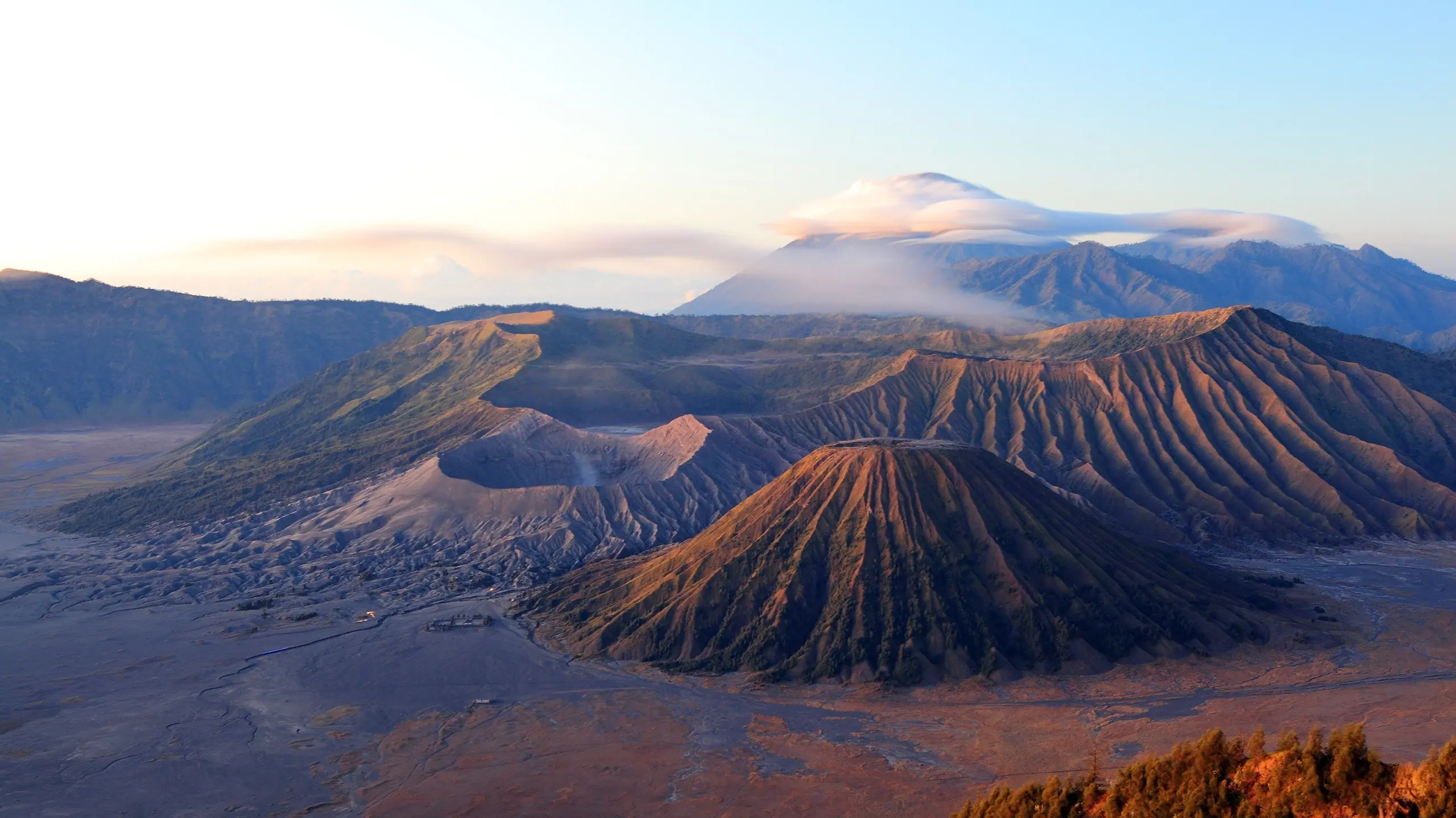 Aerial view of volcanic peaks with cloud-shrouded Mount Bromo in the background. Image credit: Shutterstock