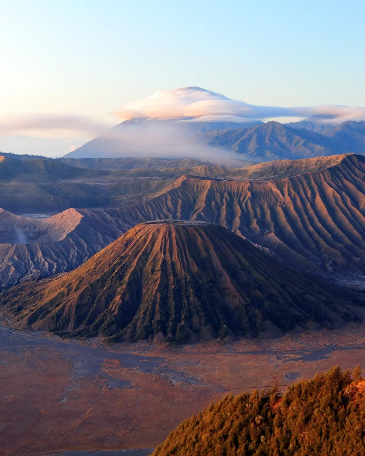 Aerial view of volcanic peaks with cloud-shrouded Mount Bromo in the background. Image credit: Shutterstock