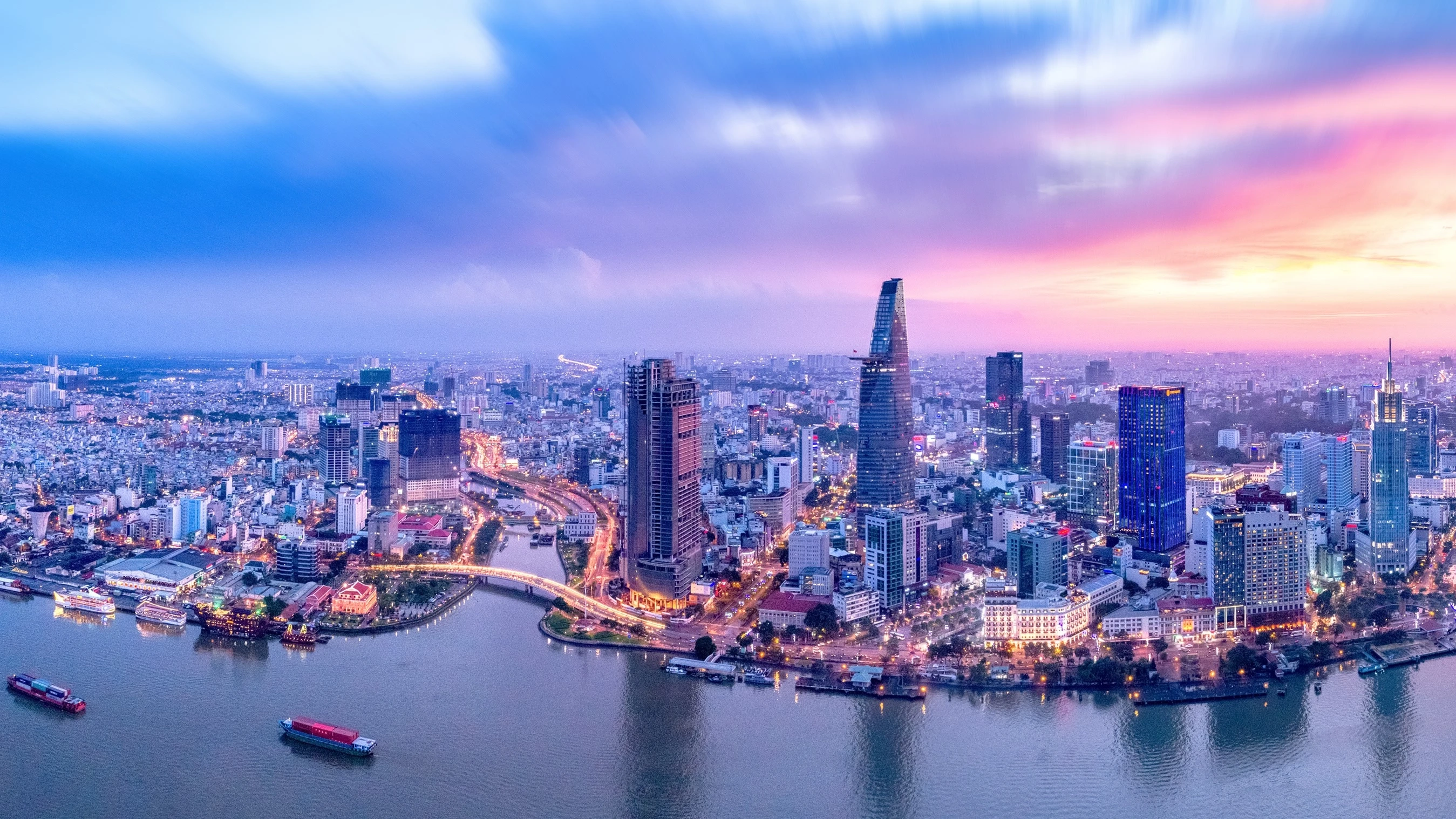 Aerial view of skyscrapers and city lights in Ho Chi Minh City’s financial and business districts, with Saigon River in the foreground, at dusk. Image credit: stock.adobe.com