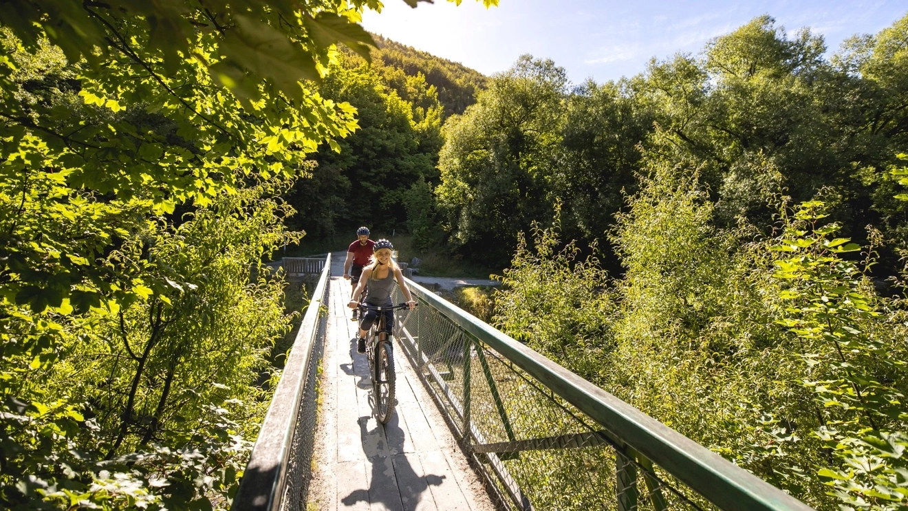 Two people on bikes, cycling through greenery in Arrowtown, near Queenstown, New Zealand. Image credit: Destination Queenstown