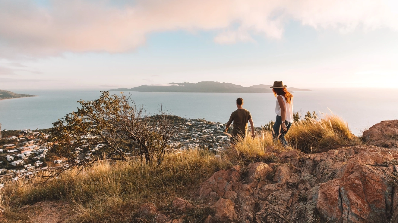 Couple at the top of Castle Hill, Townsville, with the city and Magnetic Island in the background. Image credit: Tourism and Events Queensland