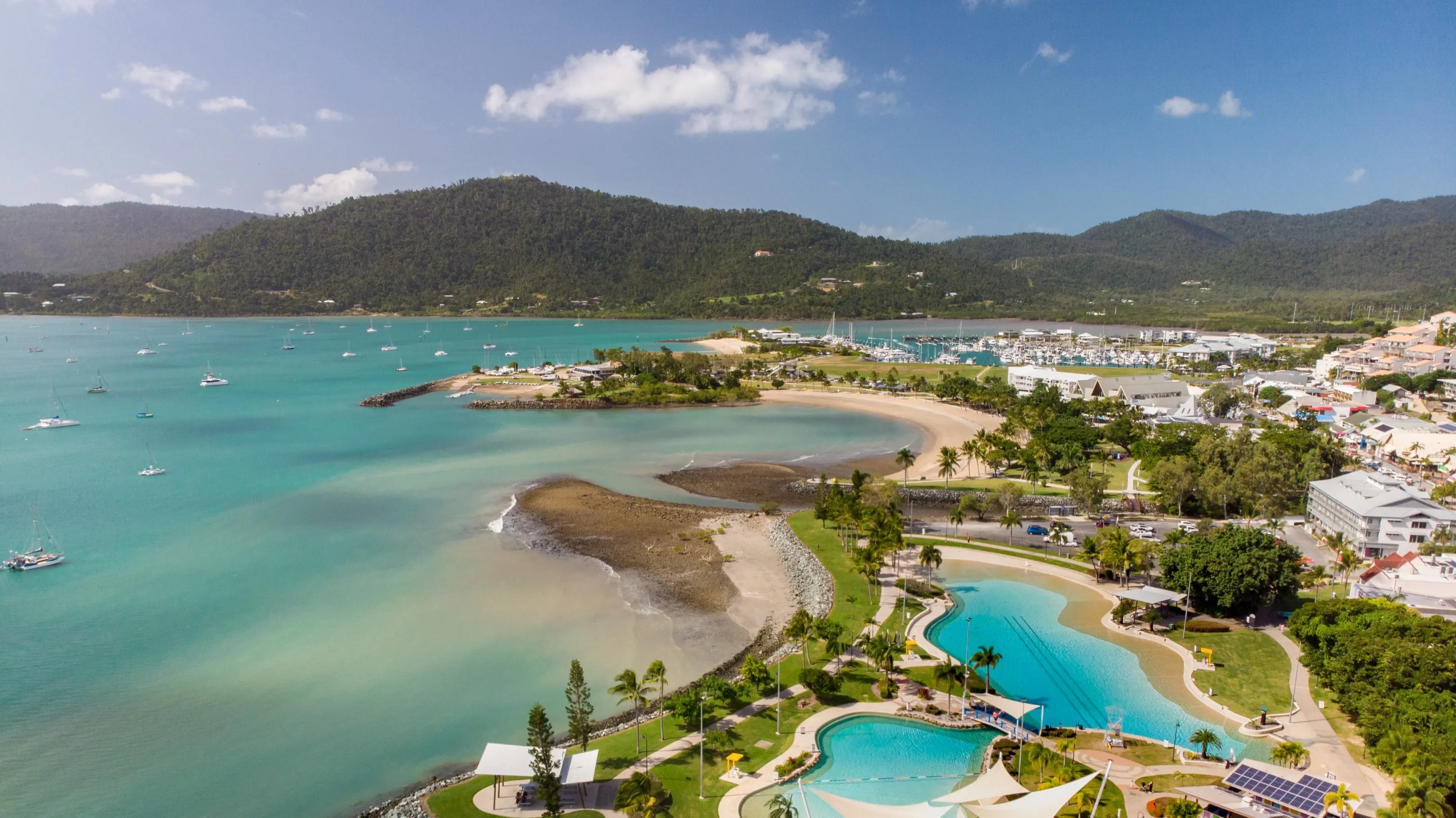 Aerial shot of Airlie Beach's waterfront with walking paths and lagoons. Image credit: Tourism and Events Queensland