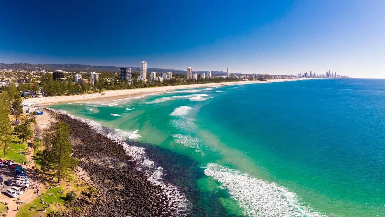 An aerial view of bright blue water and a curved shoreline at Burleigh Heads, Gold Coast, Queensland. Image credit: Shutterstock