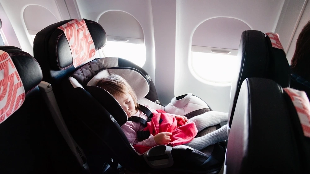 Sleeping baby in a car seat on a plane. Image credit: Shutterstock