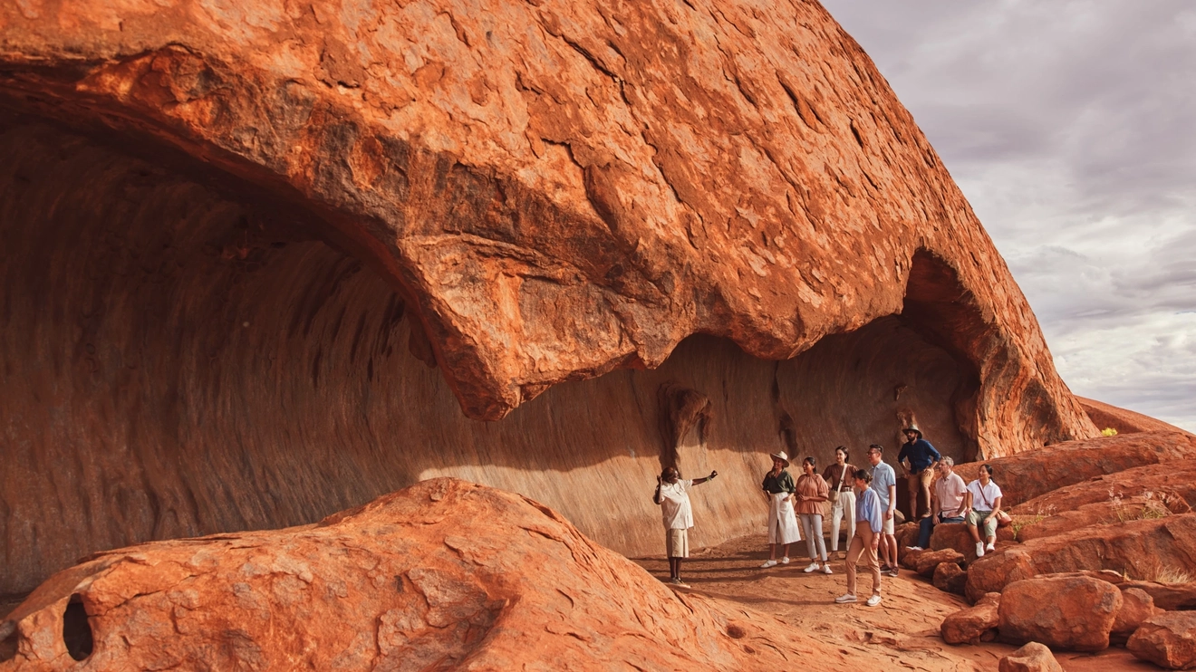 Group of people and ranger at the base of Uluru on the ranger-guided Mala walk. Image credit: Tourism NT/Tourism Australia