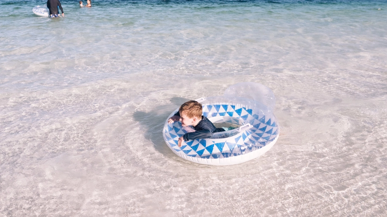Child in an inflatable ring playing in the shallow water at Lake McKenzie, K'gari (Fraser Island). Image credit: Tourism and Events Queensland