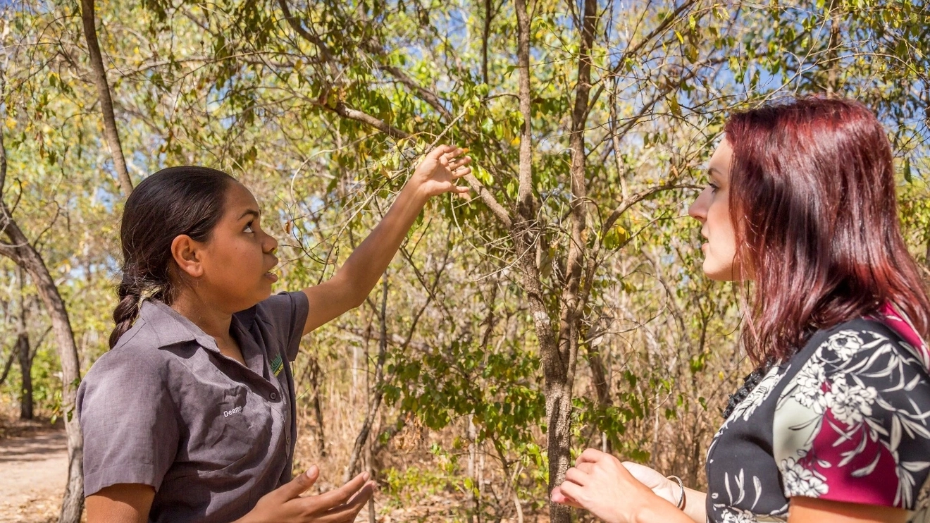 Young Aboriginal woman shows a female tourist a native plant at Pudakul, Northern Territory. Image credit: Tourism NT/Nick Pincott.