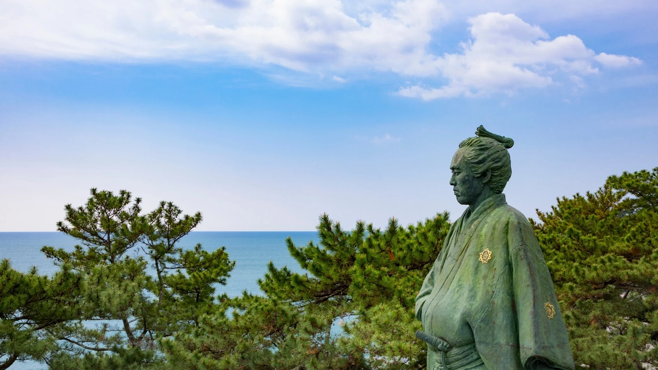 Statue of Ryoma Sakamoto at Katsurahama, with trees and ocean in background. Image credit: stock.adobe.com