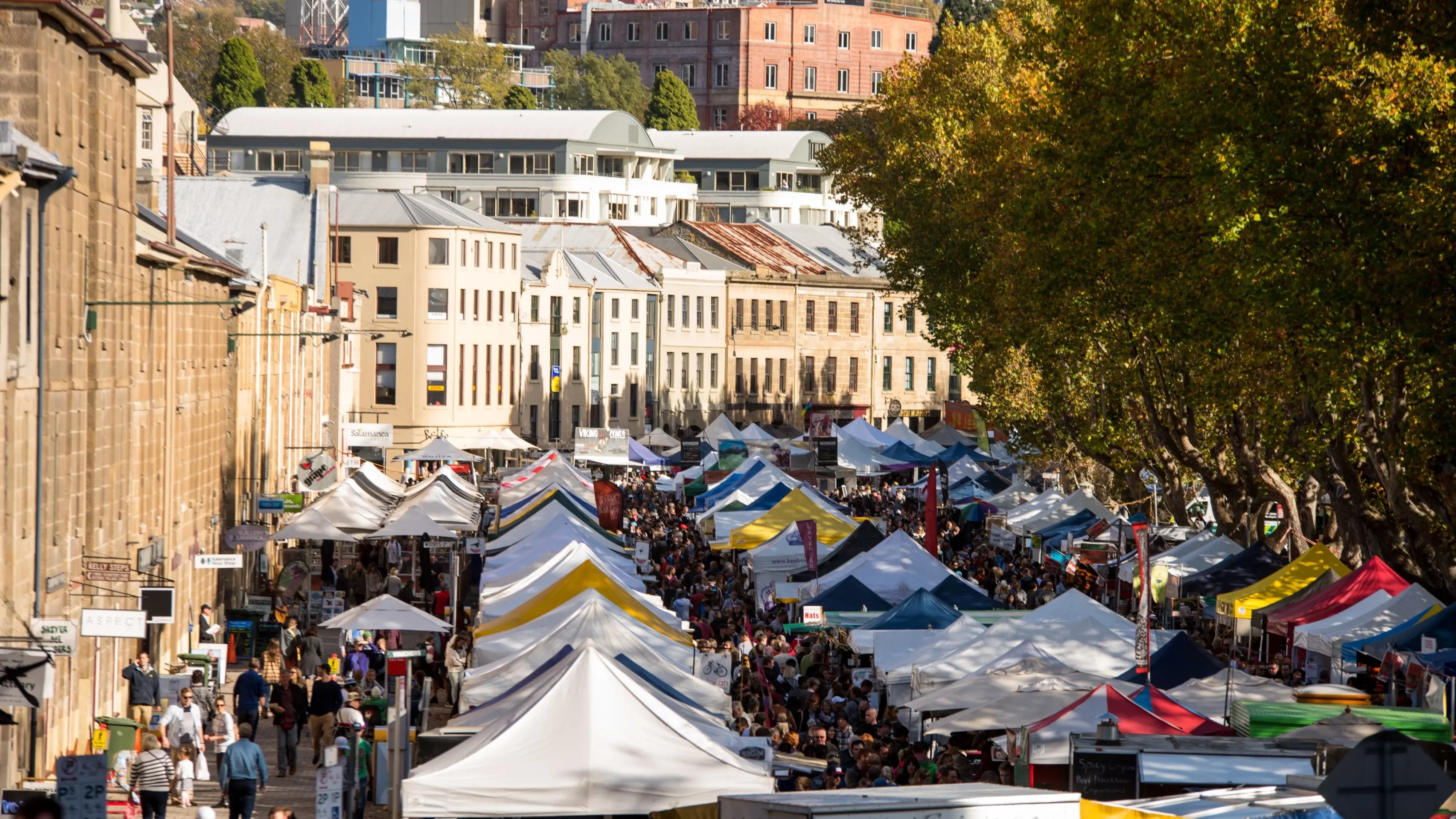 Rows of market stalls in front of sandstone buildings at Salamanca. Image credit: City of Hobart and Alastair Bett