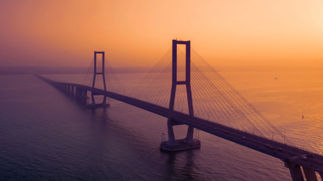 Suramadu Bridge against a red-orange sunset backdrop in Surabaya, Indonesia. Image credit: stock.adobe.com