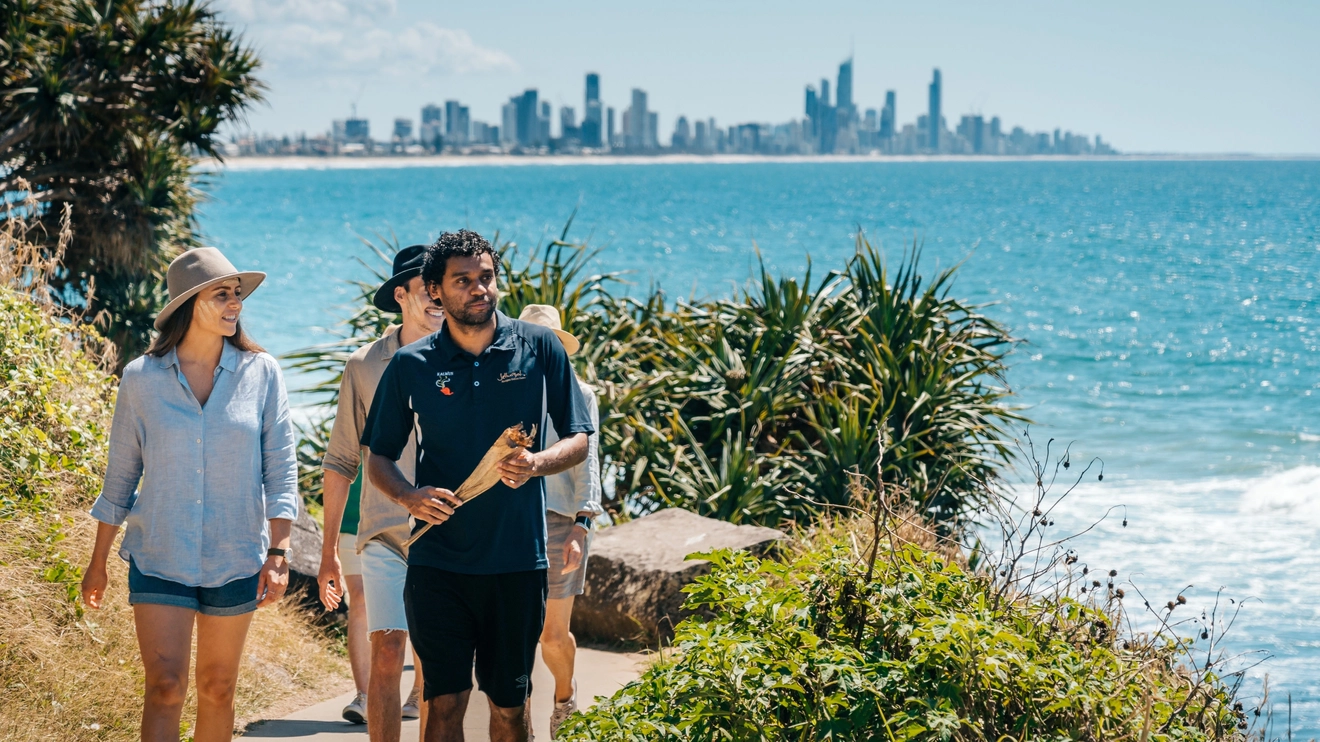 Aboriginal tour guide from Jellurgal Cultural Centre leads tourists around Burleigh Head, sharing the area's Indigenous heritage with them.