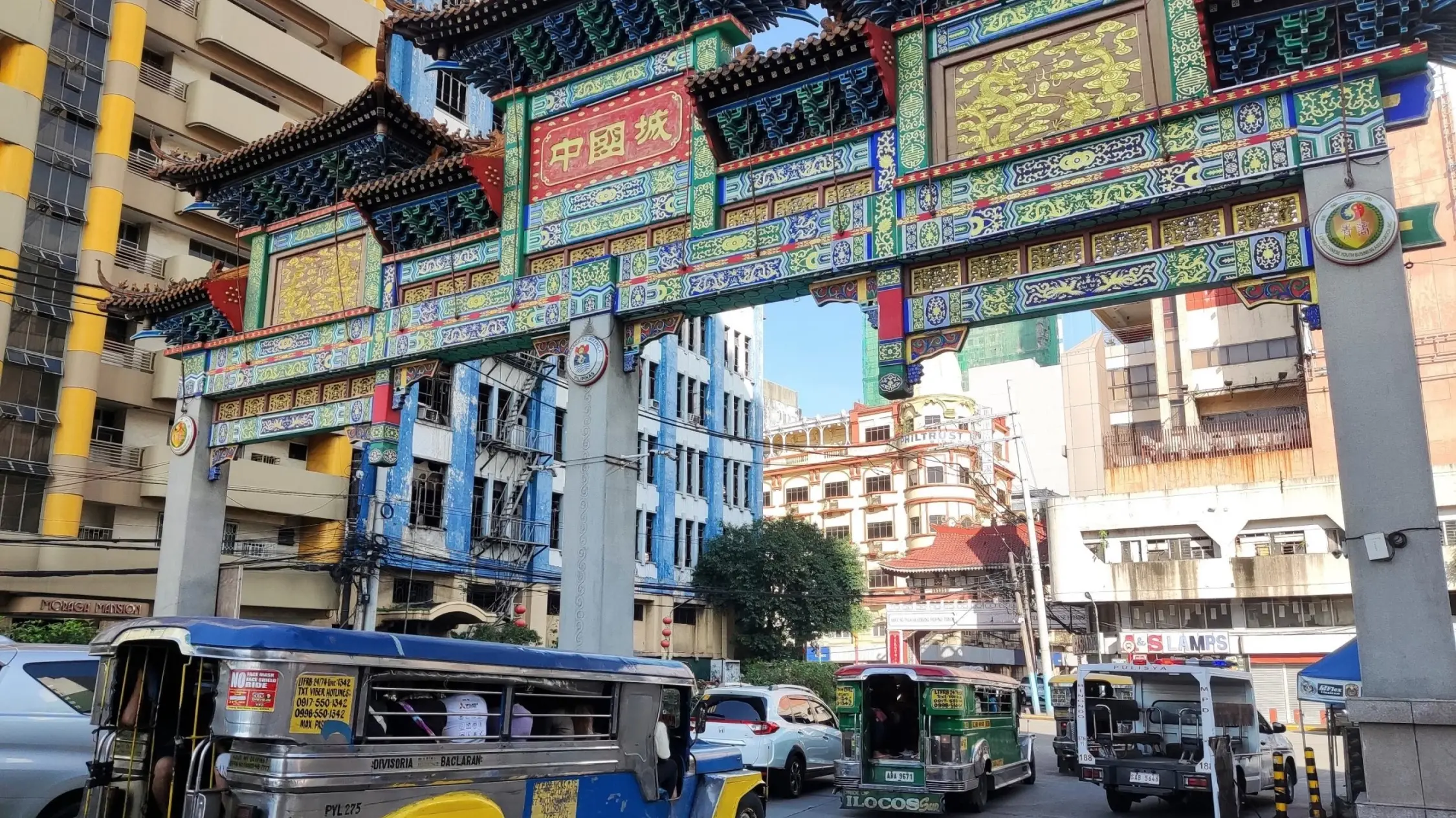 Jeepneys and cars travelling under the colourful, ornate Arch of Goodwill, the entrance to Manila's Chinatown. Image credit: tang90246 - stock.adobe.com