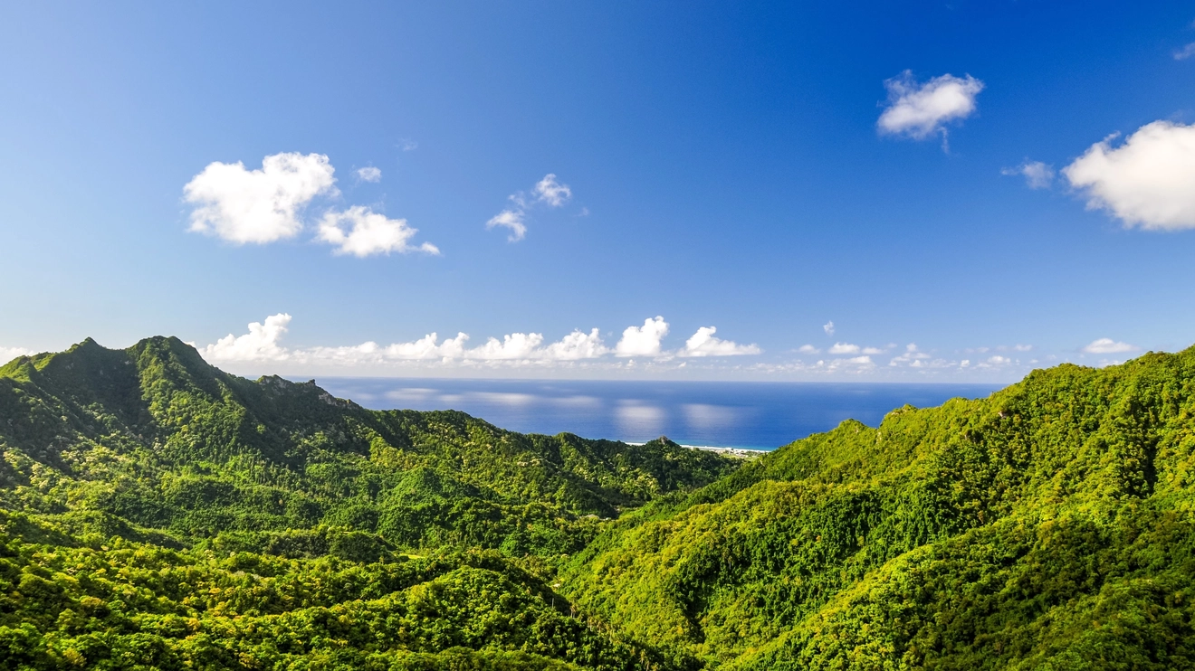 Panoramic views of lush green valleys and blue ocean in the background on a sunny day from Te Rua Manga (The Needle), Rarotonga, Cook Islands. Image credit: stock.adobe.com