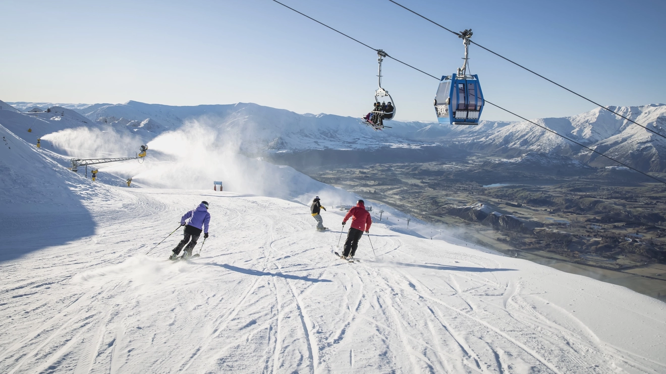 People skiing while other people ride chairlifts and gondolas overhead at Coronet Peak, Queenstown, New Zealand. Image credit: Destination Queenstown