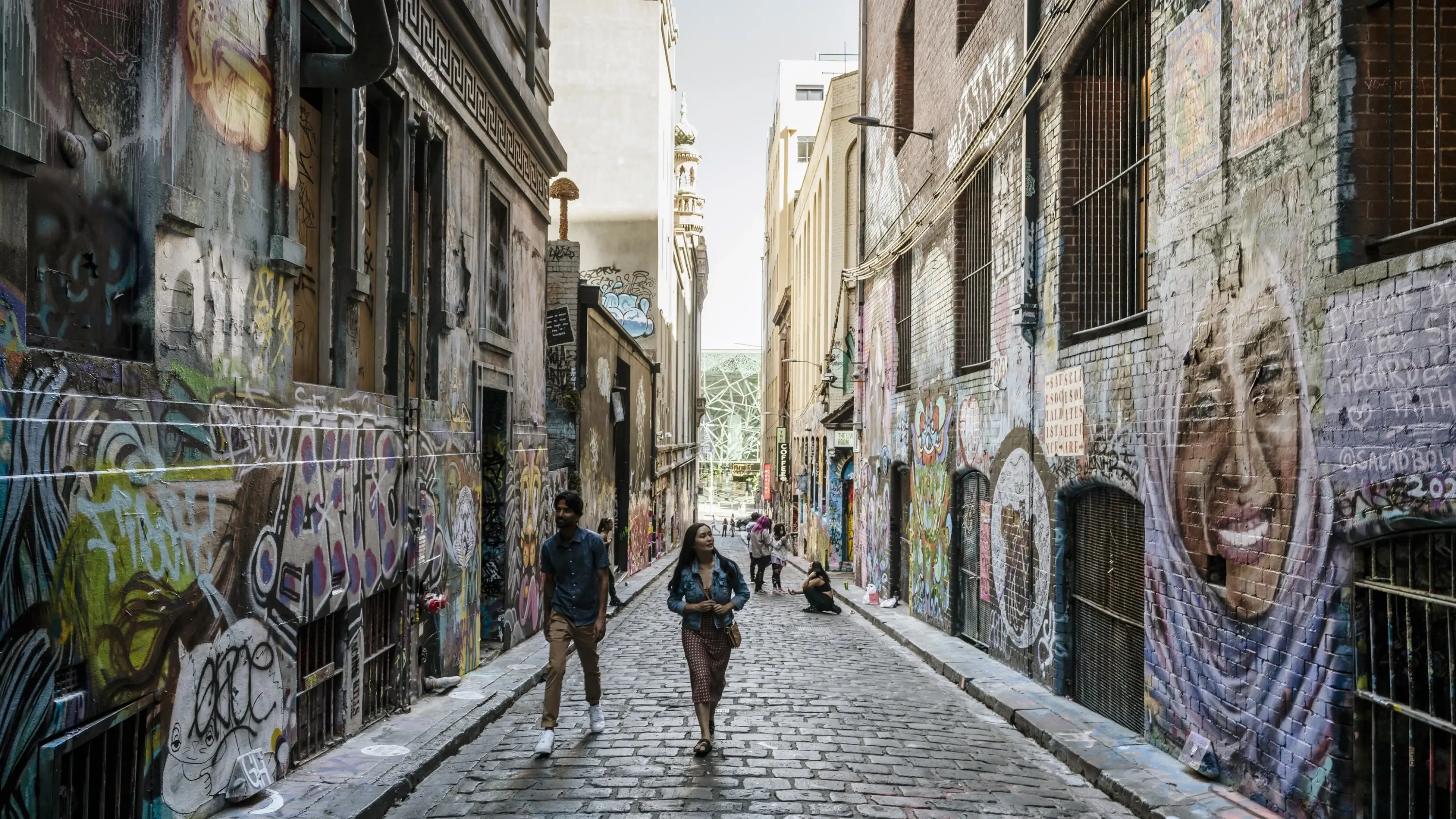 Two people walk between the street-art covered walls of Hosier Lane. Image credit: Visit Victoria