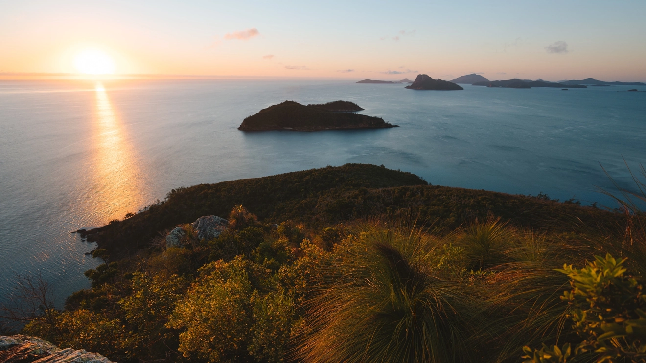 Sunrise view over water and islands from Passage Peak hiking trail. Image credit: Tourism and Events Queensland