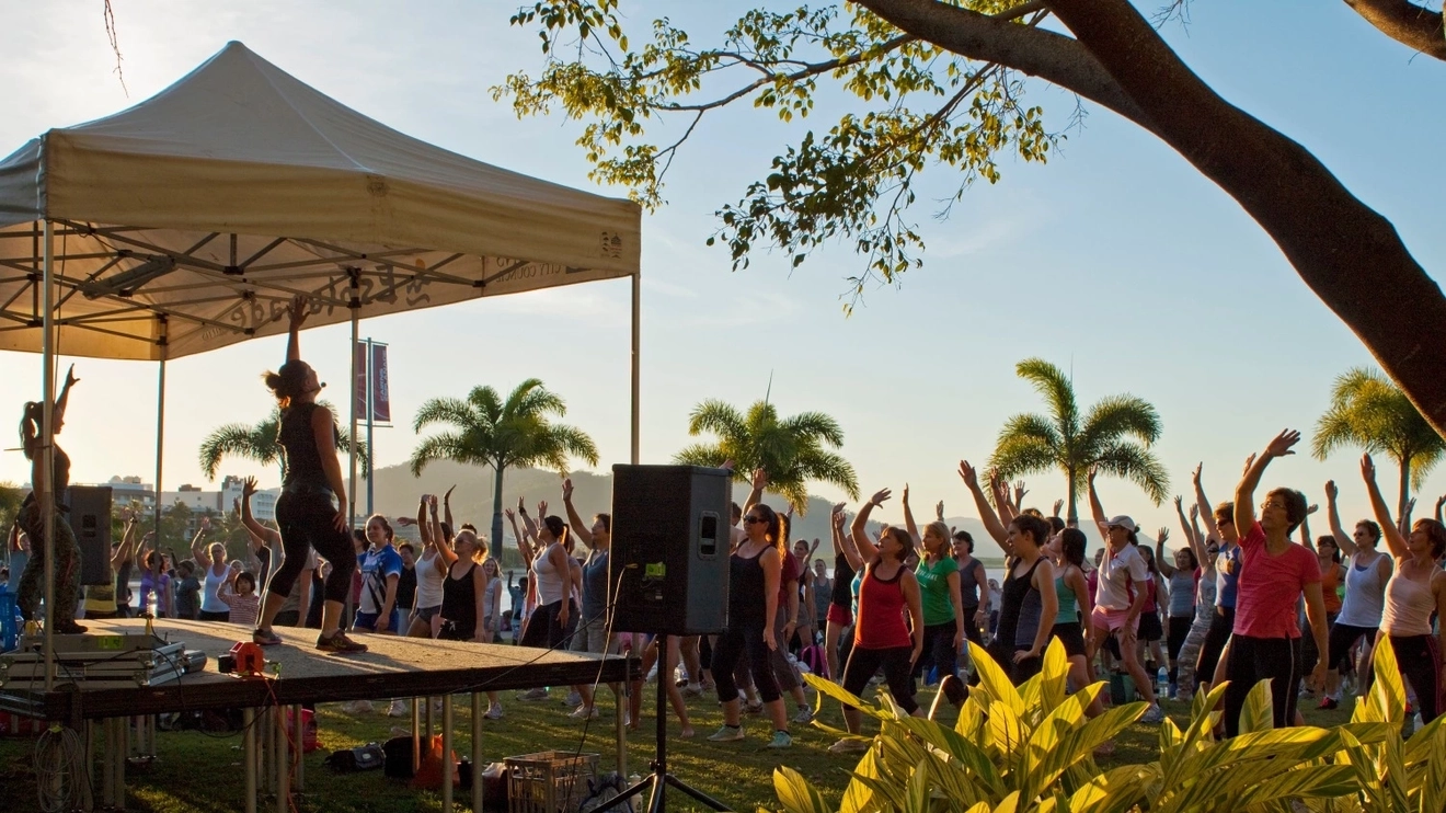 A group of people do aerobics in the park at sunset surrounded by palm trees in Cairns, Tropical North Queensland. Image credit: Shutterstock