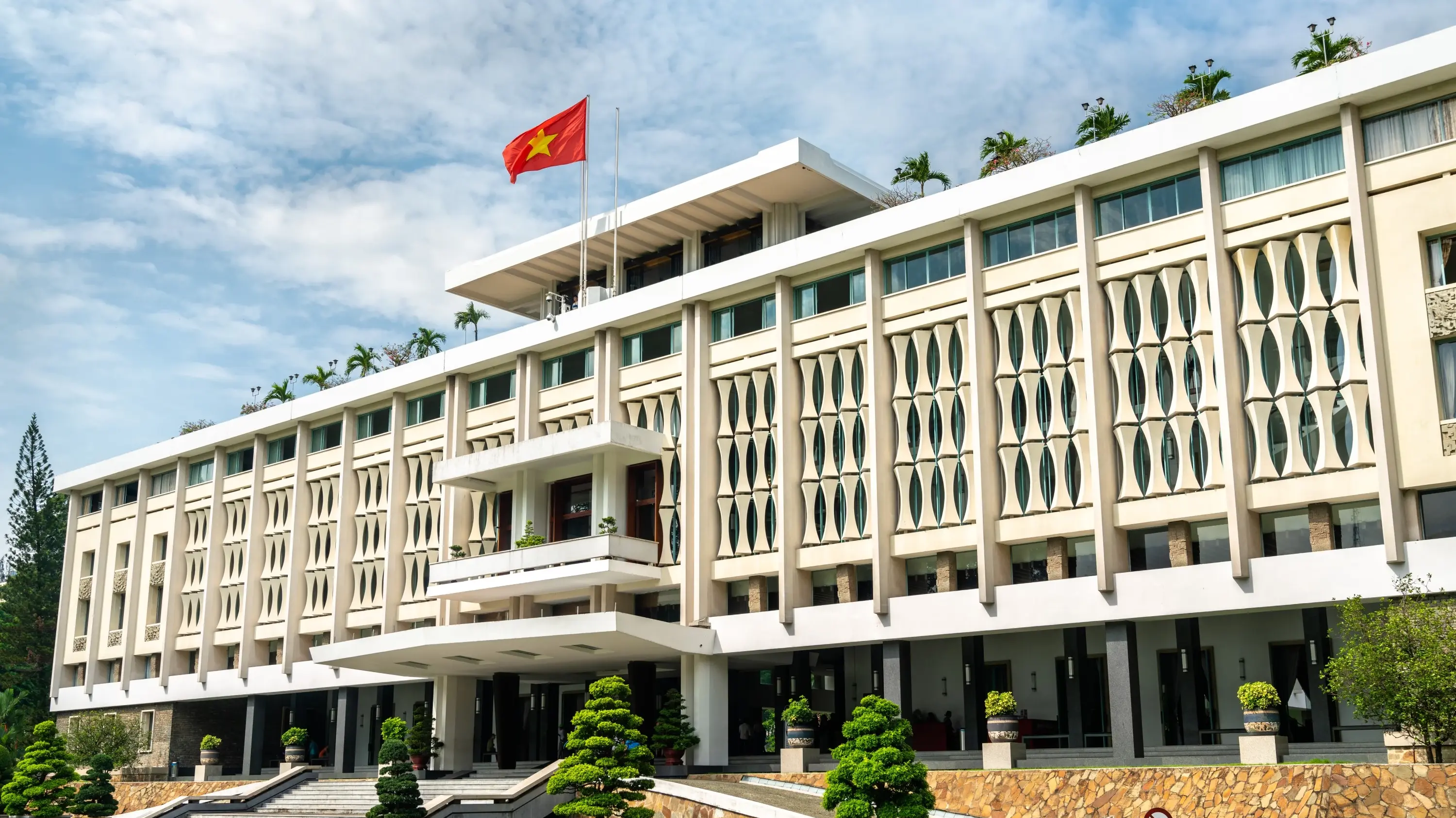 Exterior view of Ho Chi Minh City's Independence Palace with Vietnam flag flying atop. Image credit: stock.adobe.com