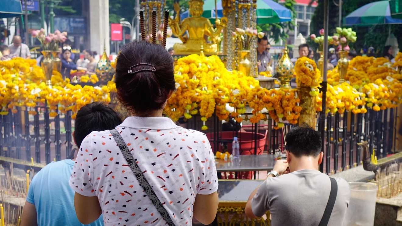 Worshippers at the marigold-encircled Erawan Shrine, Bangkok. Image credit: stock.adobe.com