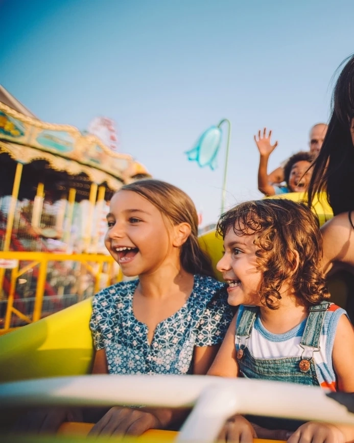 Kids enjoying theme park ride with their guardians.