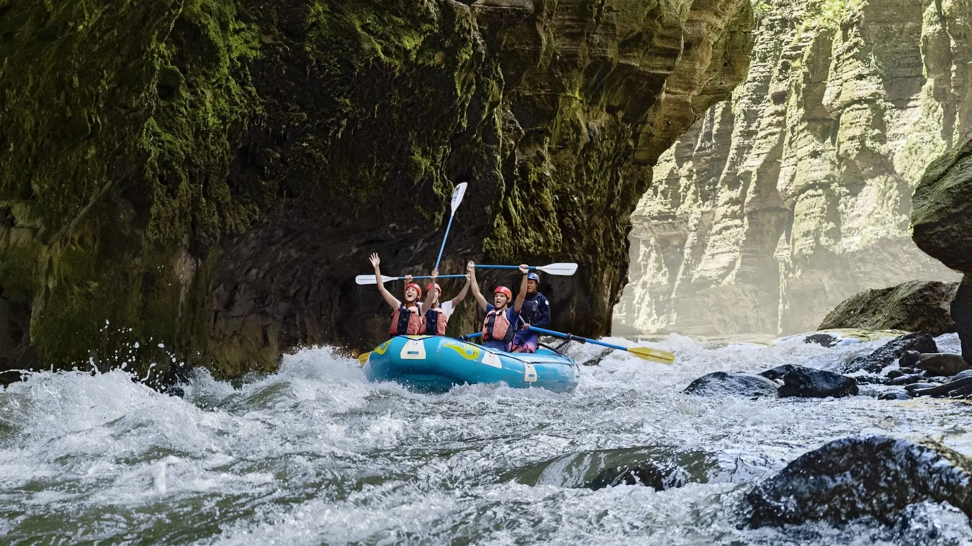 Group of people on a raft in rapids in a deep canyon on the Upper Navua River, Fiji. Image credit: Tourism Fiji