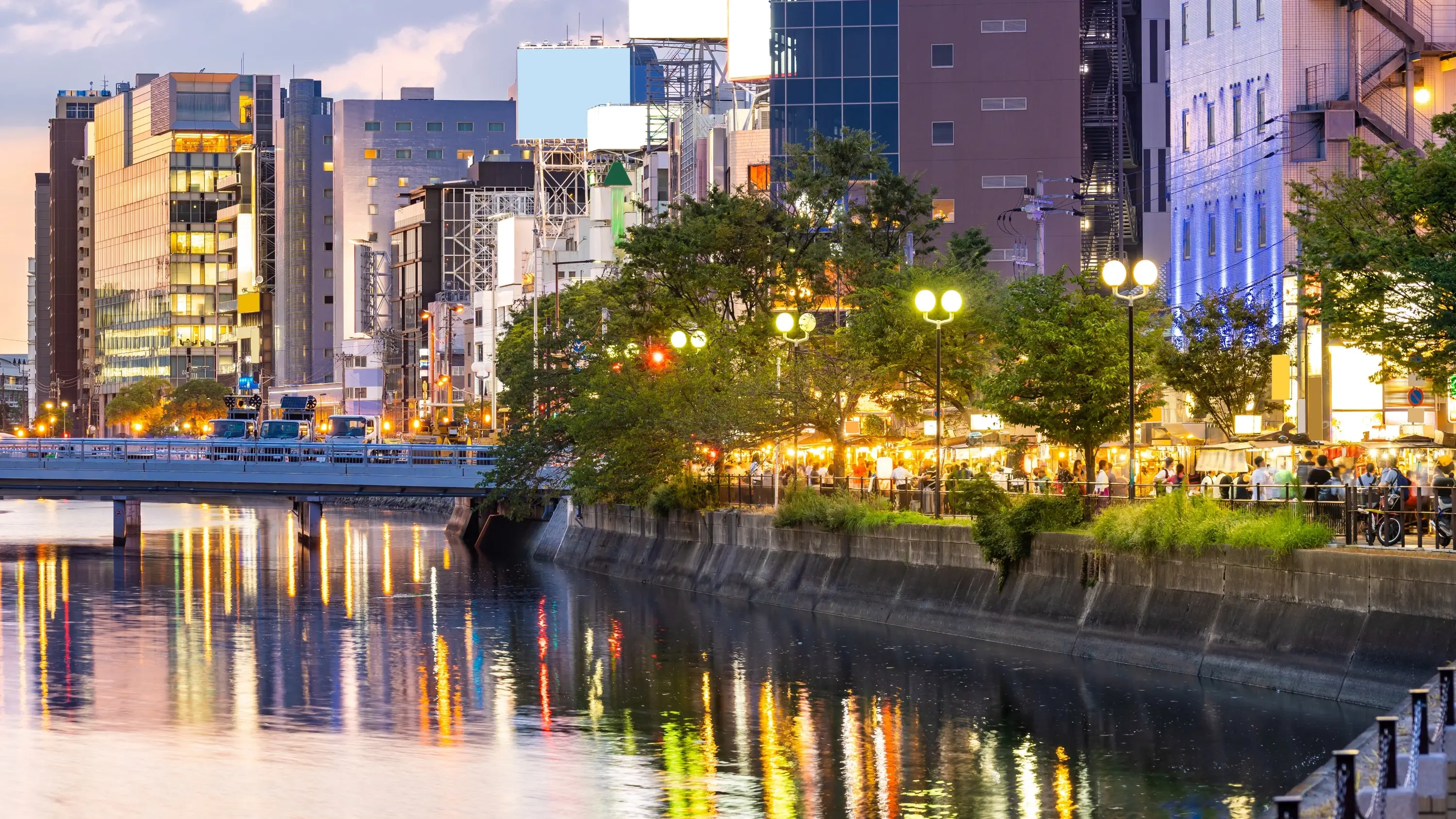 The lights of Fukuoka city reflected in the Naka river with *yatai* street-food stalls along the river bank. Image credit: stock.adobe.com