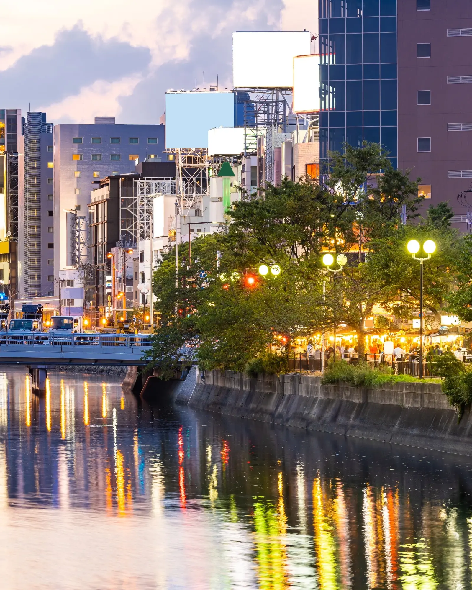 The lights of Fukuoka city reflected in the Naka river with *yatai* street-food stalls along the river bank. Image credit: stock.adobe.com