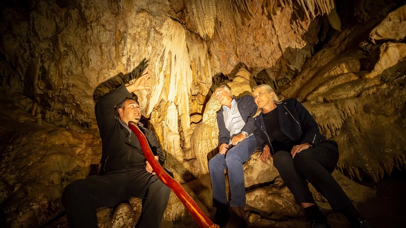 In Ngilgi Cave, Western Australia, Aboriginal tour guide plays didgeridoo for two tourists. Image credit: Tourism Western Australia
