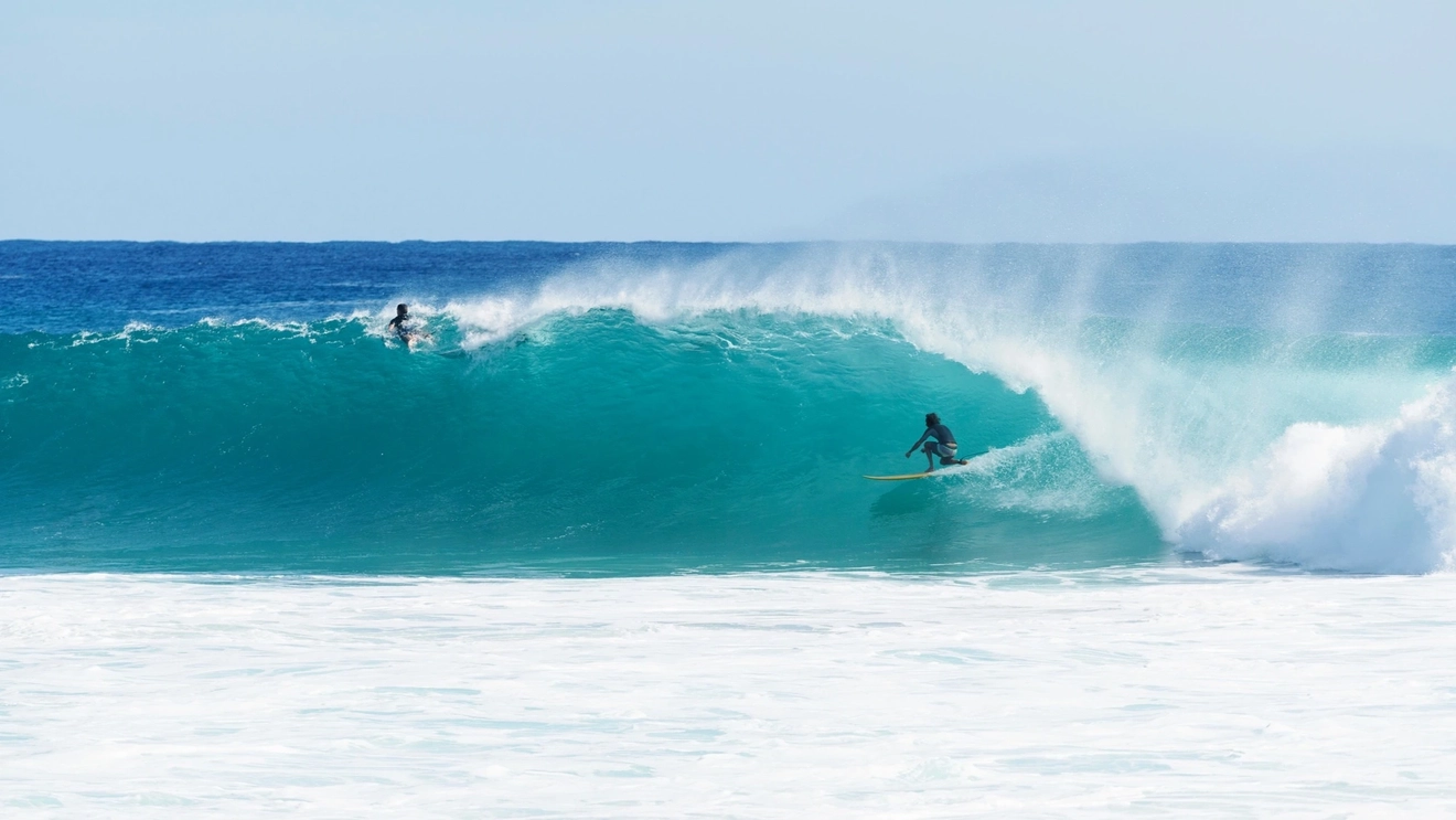 Two surfers riding at wave at Kirra on the Gold Coast.