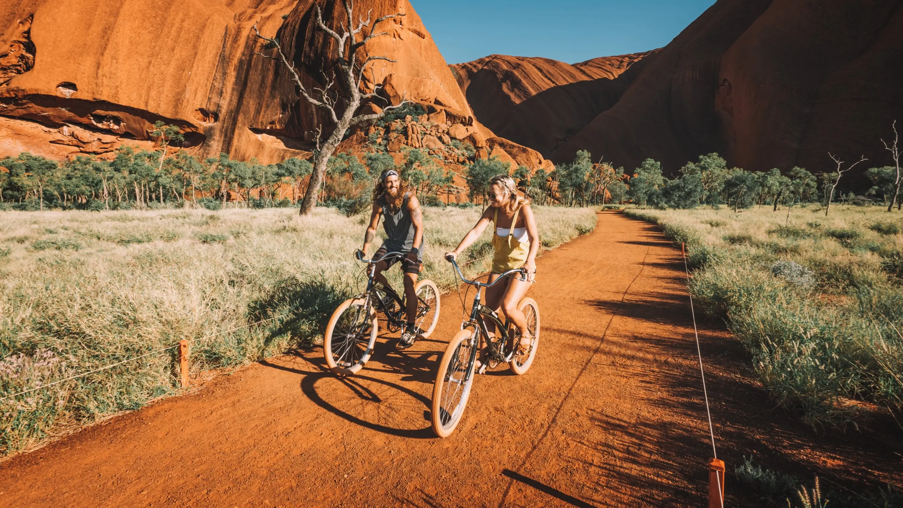 Two people riding bikes on the base track of Uluru. Image credit: Tourism NT/Laura Bell