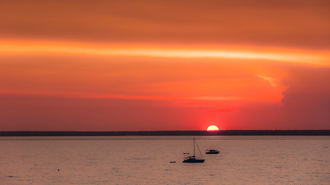 A bright orange sunset over still waters at Darwin Harbour. Image credit: Tourism NT/Jules Ingall