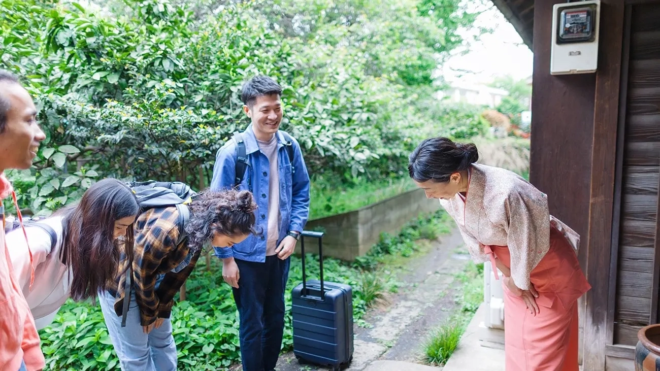 Visitors greet a Japanese woman by bowing.
