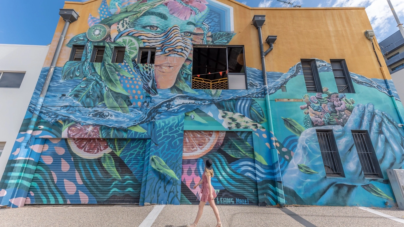 Woman admires colourful street-art mural on building, Townsville. Image credit: Tourism and Events Queensland