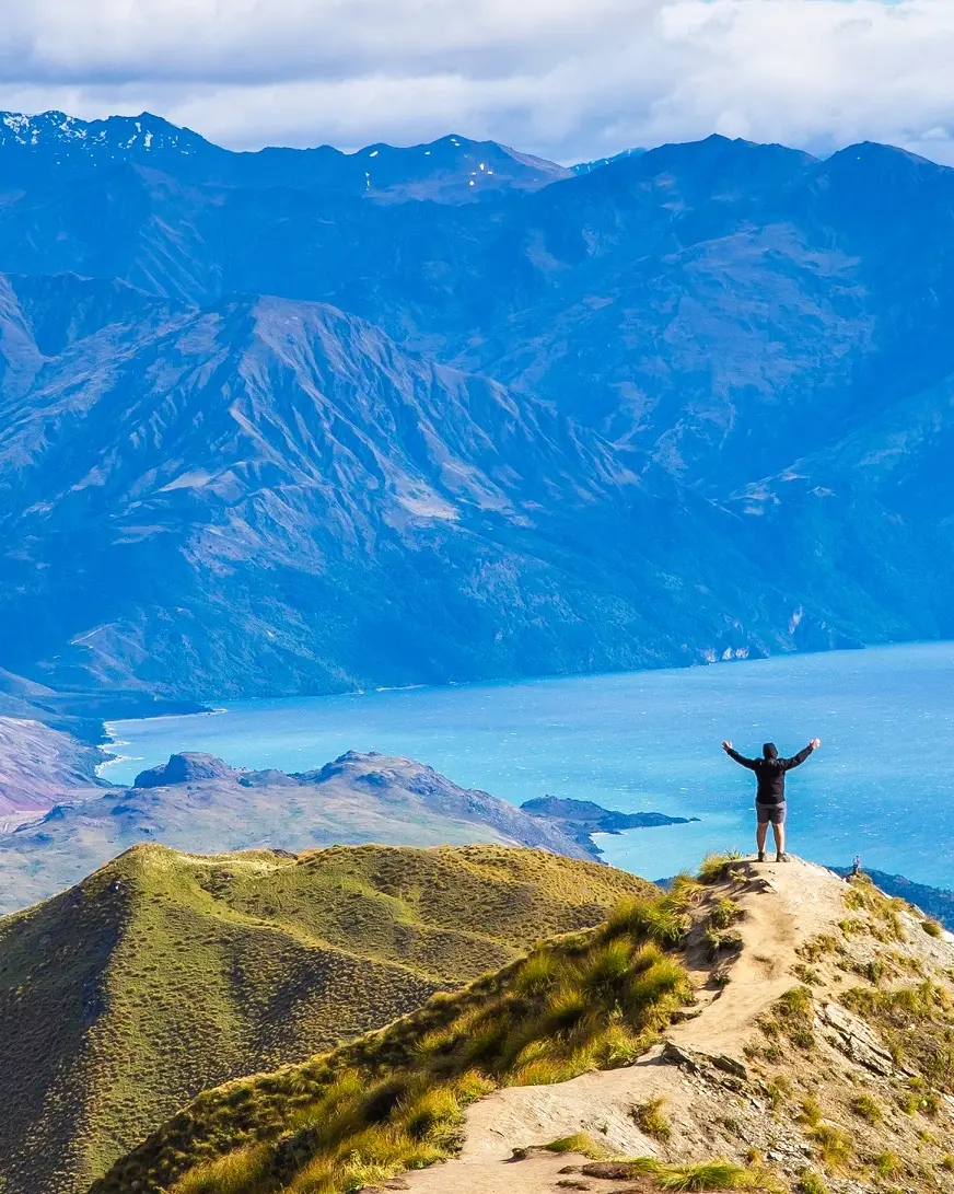 Mountain climber enjoys the spectacular view from the top of Roy's Peak, overlooking Lake Wanaka. Image credit: stock.adobe.com