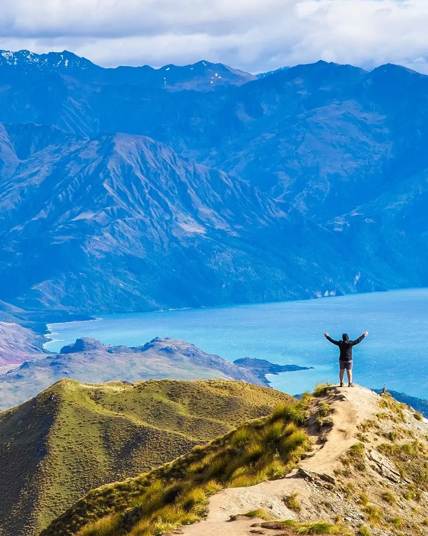 Pendaki gunung menikmati pemandangan spektakuler dari puncak Roy's Peak, menghadap Danau Wanaka. Kredit gambar: stock.adobe.com