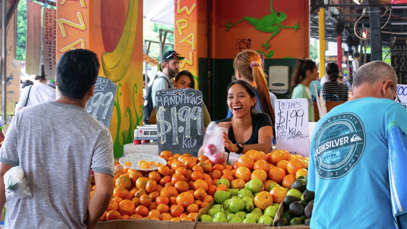 People shopping at colourful fruit stalls at Rusty's Markets, Cairns, Tropical North Queensland. Image credit: Shutterstock
