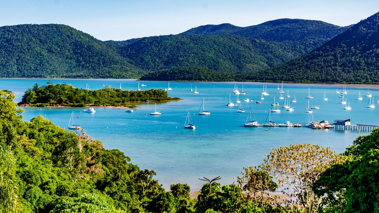 A view of boats on blue water and the hills of Conway National Park in the background, Whitsunday Coast, Queensland. Image credit: Shutterstock